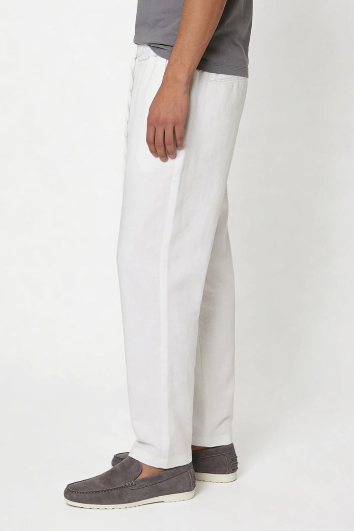 Man wearing white linen drawstring trousers relaxed straight fit lightweight summer linen pants side view