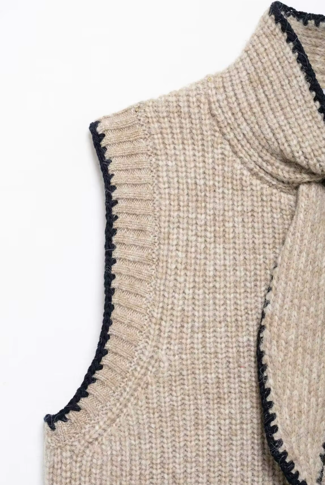 Beige knitted vest with black trim on a white background