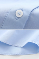 Close-up of a light blue shirt with a button and collar detail.