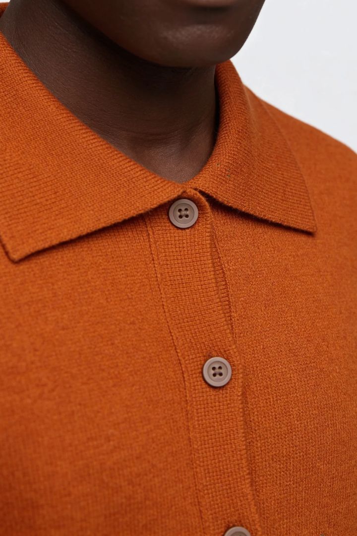 Men’s 100% wool knit cardigan sweater in orange with button front and classic collar design close-up