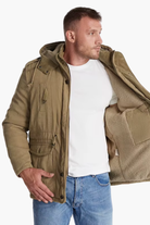 Man wearing a brown jacket with a hood on a white background