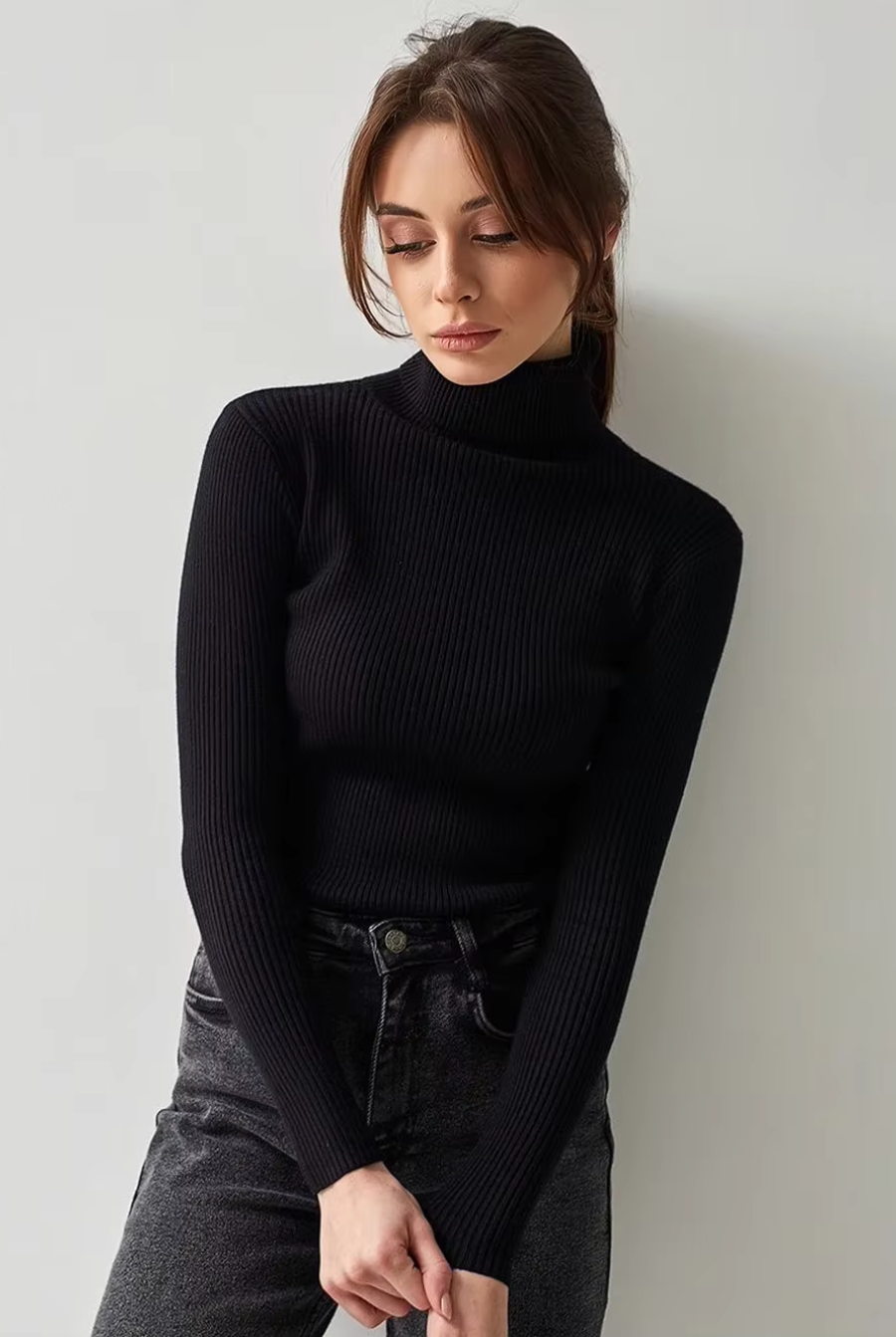 Model styling black ribbed turtleneck sweater with high-rise jeans