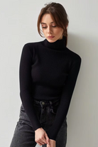 Model styling black ribbed turtleneck sweater with high-rise jeans