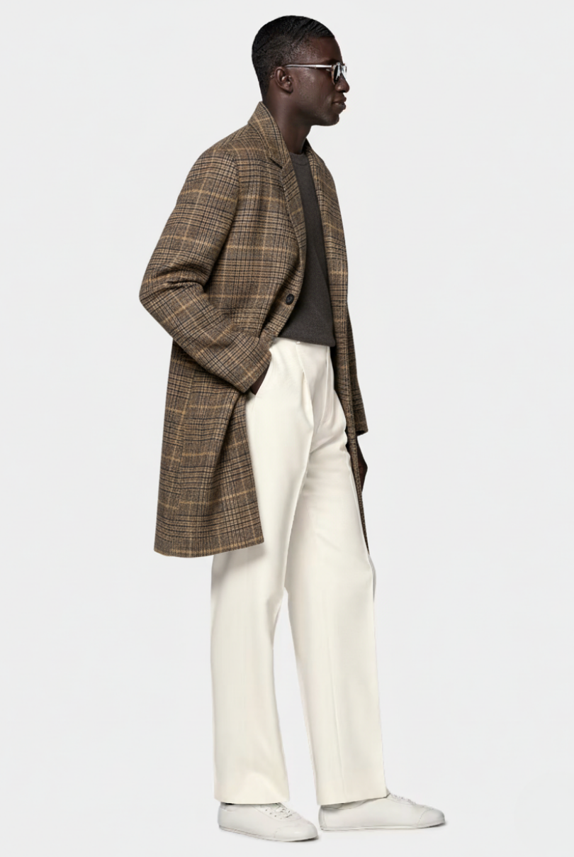 Man wearing a plaid coat, gray shirt, white pants, and white shoes on a white background