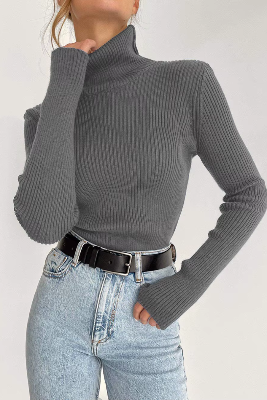 Woman wearing grey ribbed turtleneck sweater with jeans