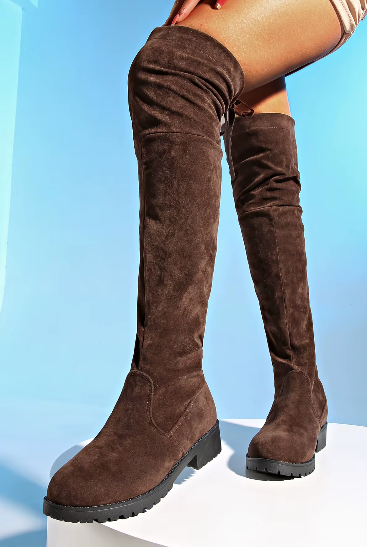 Brown suede knee-high boots on a light blue background