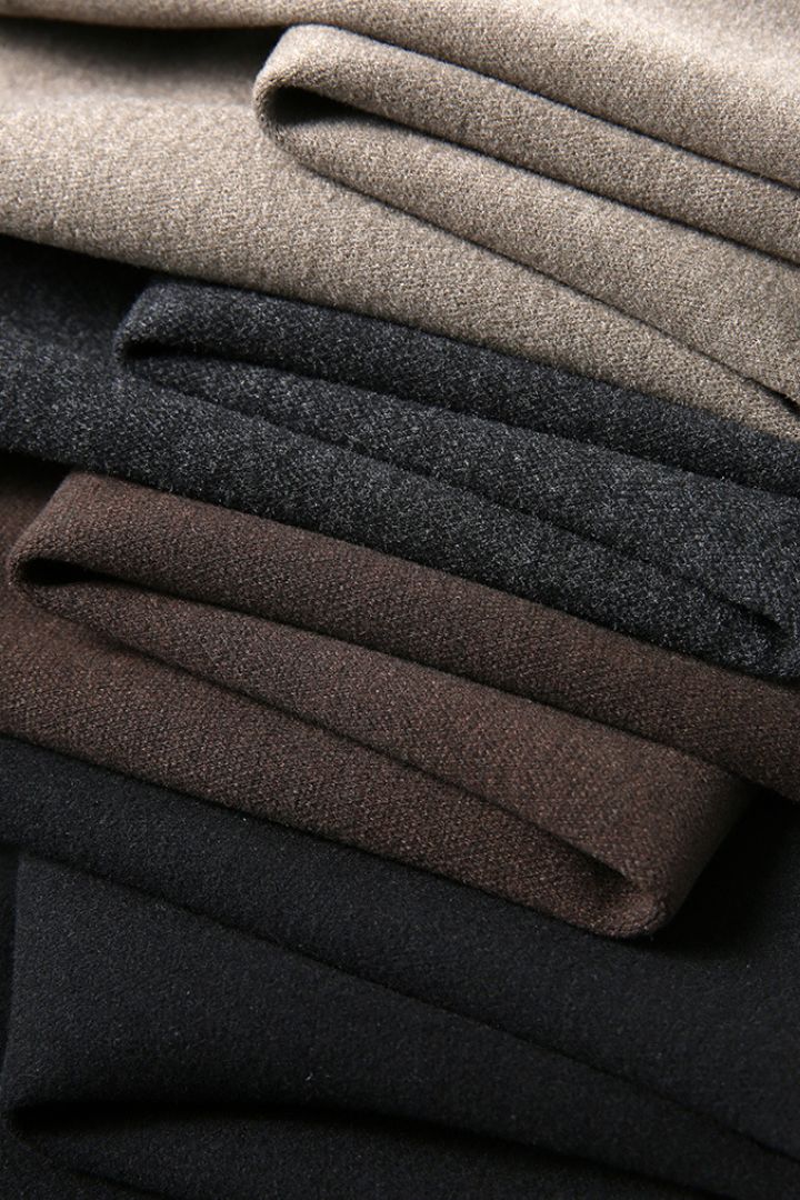 Stack of folded dark gray, black, beige and brown fabric drawstring trousers of Lavencio.