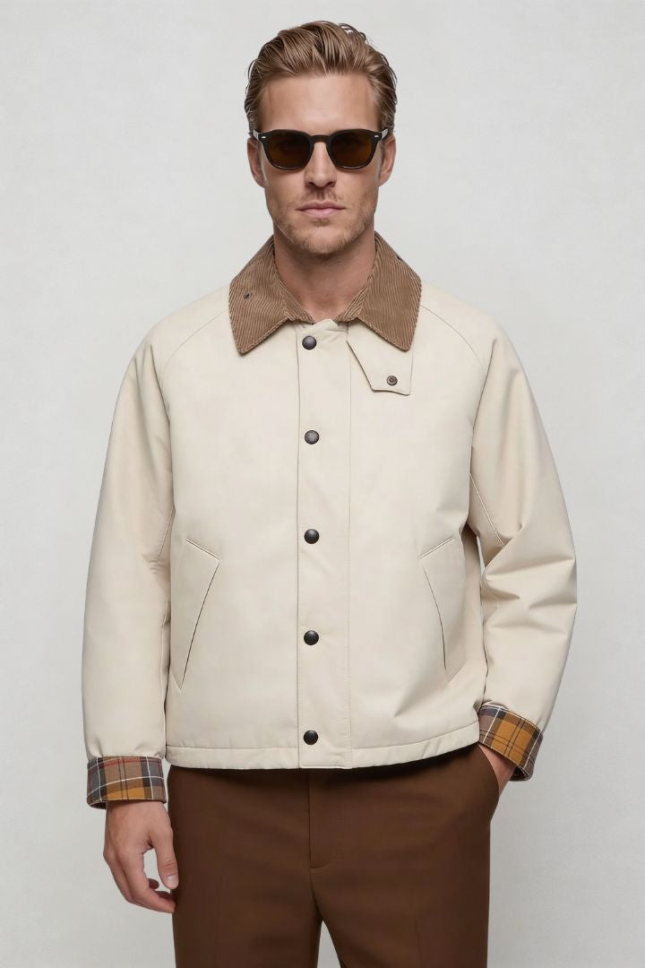 Man wearing a cream jacket with brown collar and sunglasses on a white background