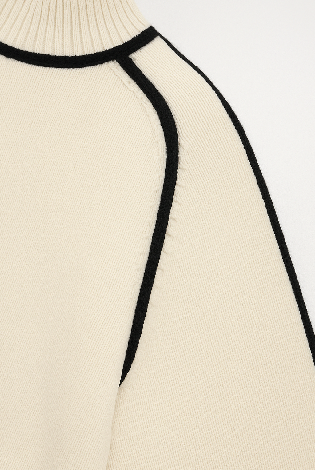 Close-up of a beige sweater with black trim on a white background
