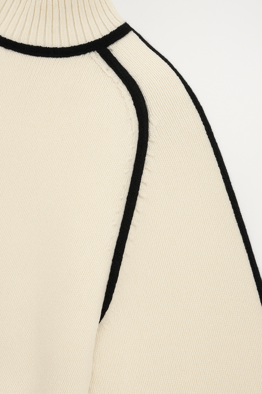 Close-up of a beige sweater with black trim on a white background