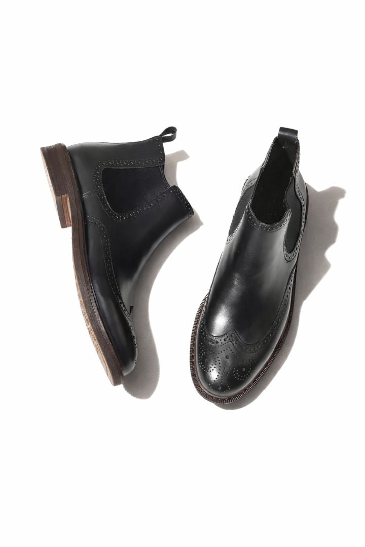 Men’s leather brogue Chelsea boots in black with wingtip detailing and classic slip-on ankle boot silhouette front view