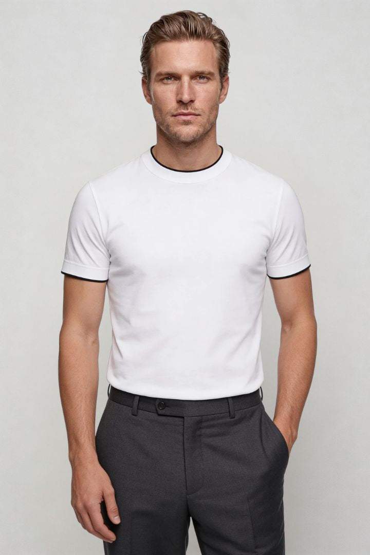 Man wearing the white Logan t-shirt and dark pants against a plain background