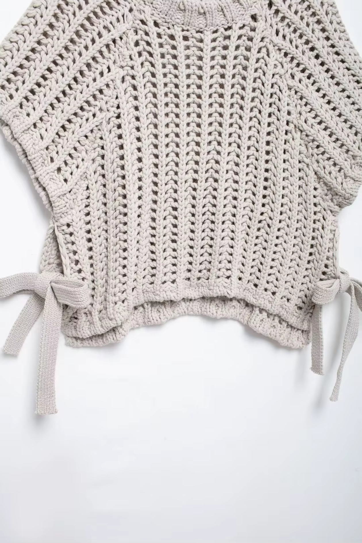 Knitted gray top with tie details on a white background