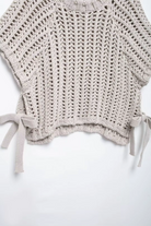 Knitted gray top with tie details on a white background