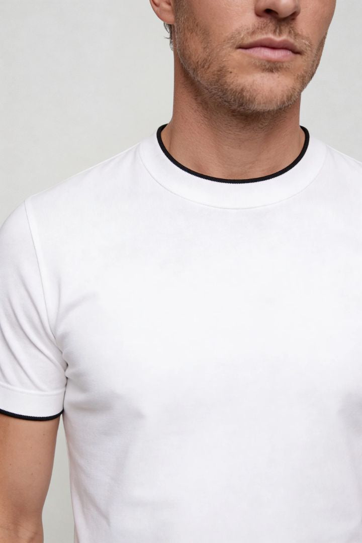 Man wearing the white Logan t-shirt and dark pants against a plain background close-up