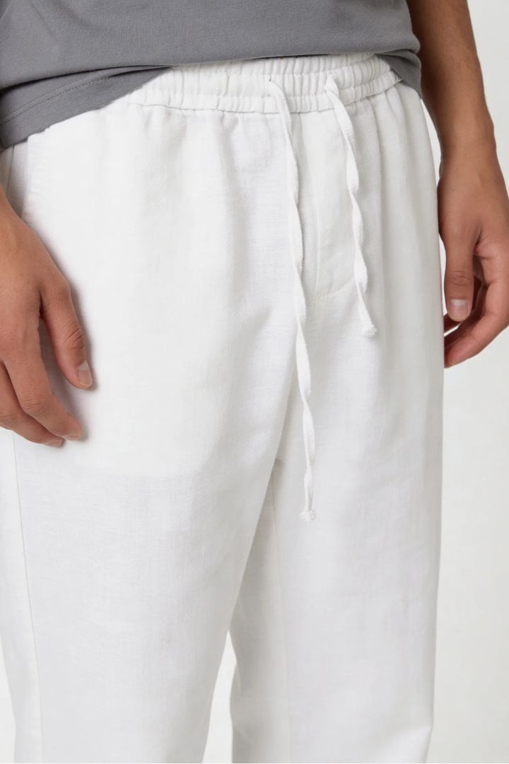 Man wearing white linen drawstring trousers relaxed straight fit lightweight summer linen pants close-up