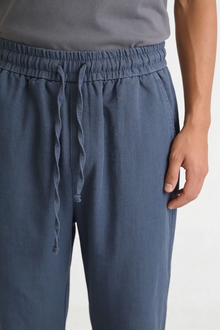 Men wearing steel blue linen drawstring trousers relaxed straight fit lightweight summer linen pants close-up