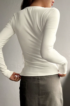 White long-sleeve top worn by a person on a plain background