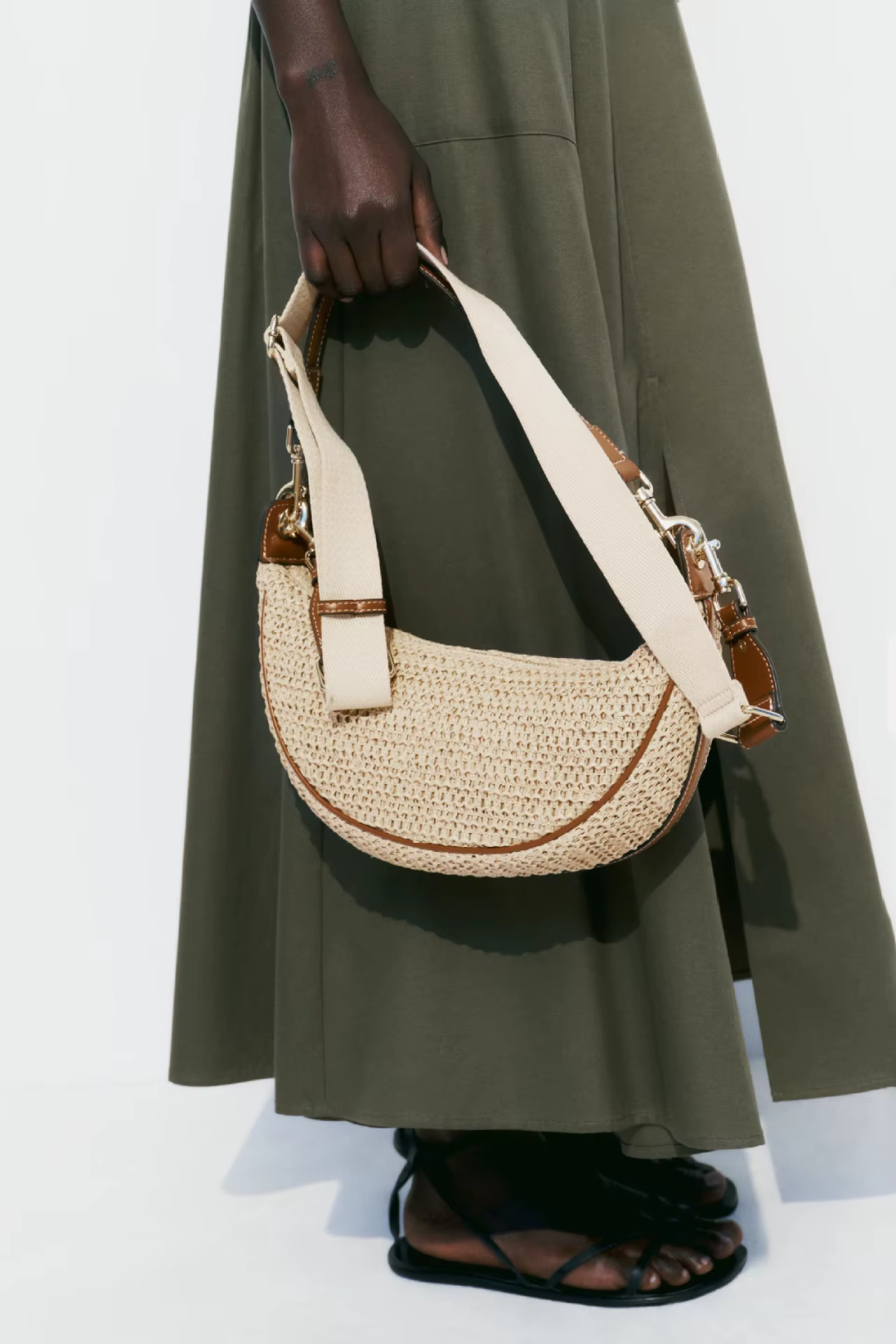 Person holding a woven handbag with a plain background