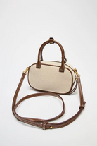 Beige handbag with brown handle and strap on a white background