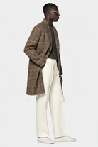 Man wearing a plaid coat, gray shirt, white pants, and white shoes on a white background