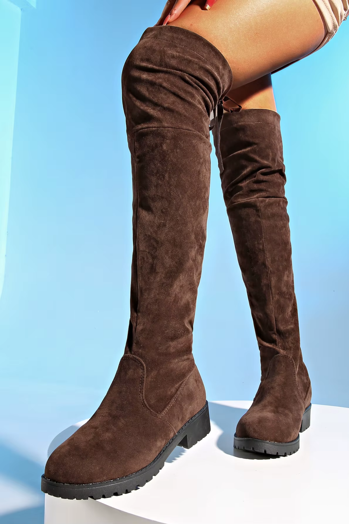 Brown suede knee-high boots on a light blue background