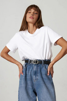 Woman wearing a white t-shirt and blue jeans on a plain background