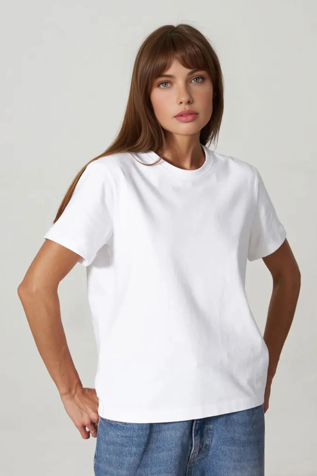 Woman wearing a plain white t-shirt and blue jeans against a light gray background