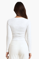 Person wearing a white long-sleeve top and pants on a white background