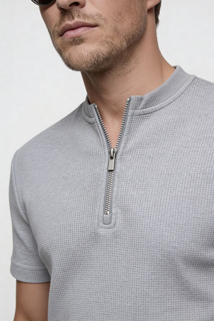 Man wearing a gray short-sleeve shirt with a zipper detail on a white background